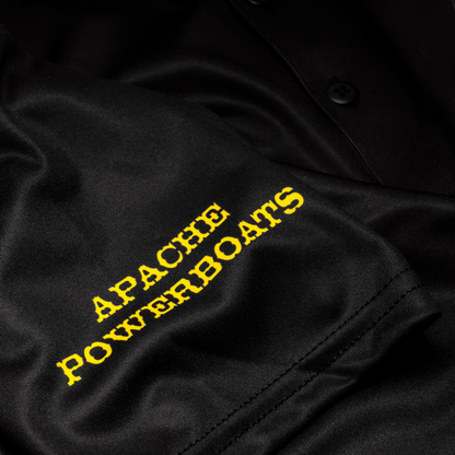 Close-up of Apache Powerboats sleeve logo on black performance polo shirt